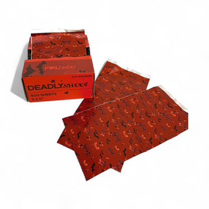 Red paper sheets with black patterns and a box labeled 'DEADLYsweet' on a white background
