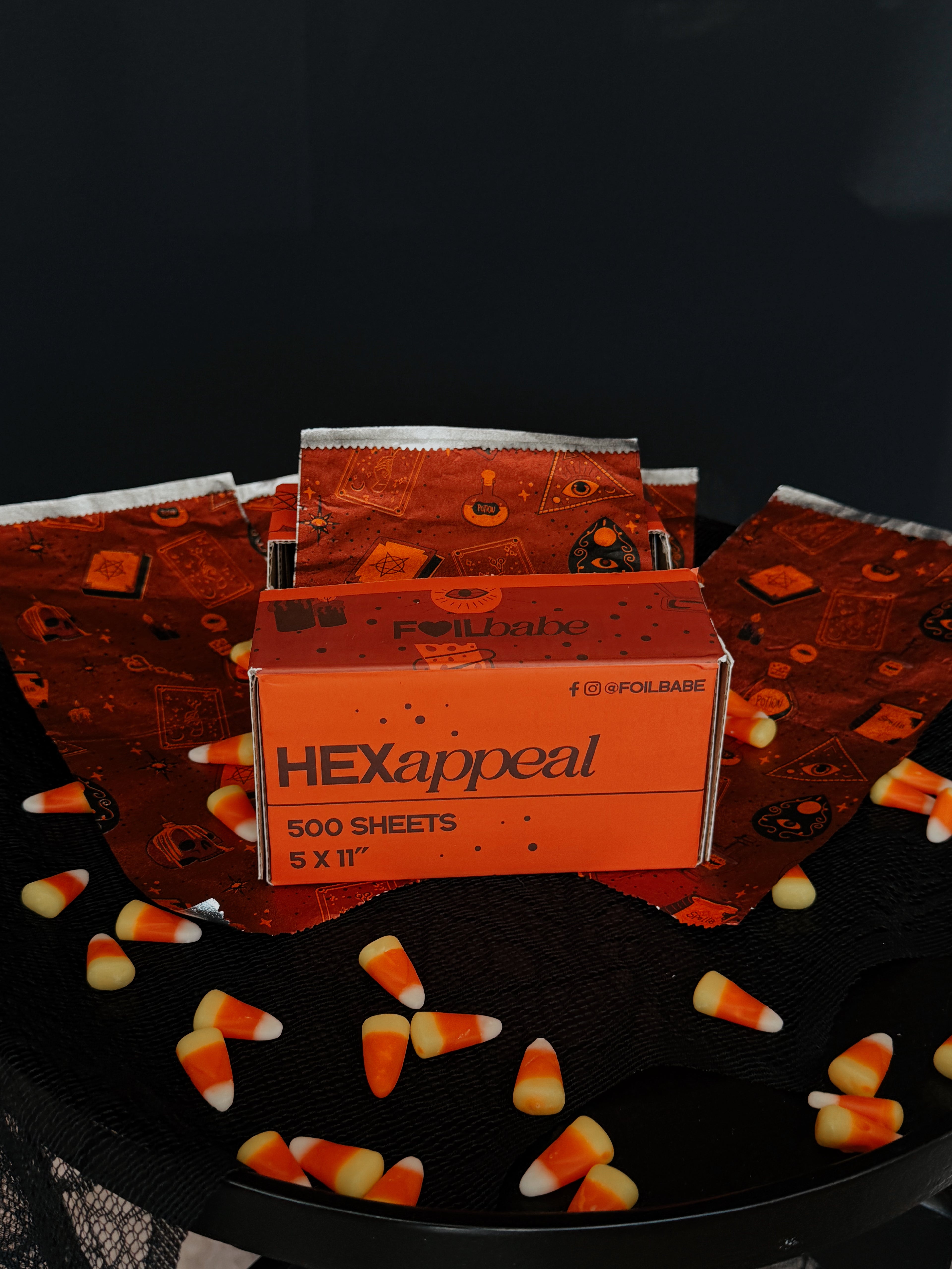 Box of 'HEXappeal' paper with candy corn on a dark background